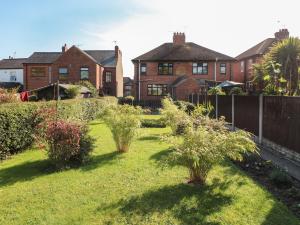 a yard with trees and bushes in front of a house at Hideaway in Alfreton