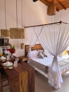 a bedroom with a bed with a mosquito net at LOFT café da manhã e piscina ! in Trancoso