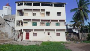 a white building with a red door and a palm tree at Manama Suites Lamu in Lamu