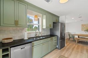 a kitchen with green cabinets and a stainless steel refrigerator at The Sunny Side-Pensacola Beach, 600 feet to Gulf, Private/Heated Pool, Games, Gear in Pensacola Beach