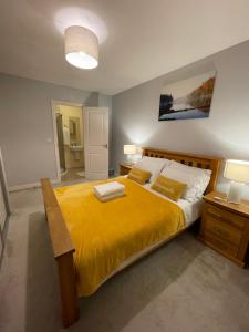 um quarto com uma cama grande e um cobertor amarelo em Holiday Home In Cardiff, Sleeps 8 em Cardiff