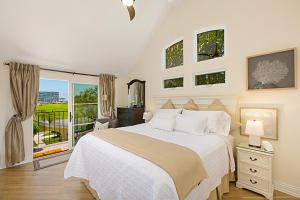 een witte slaapkamer met een bed en een raam bij Coronado Seaside Cottage in San Diego