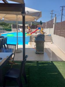 einen Pool mit einem Sonnenschirm, Stühlen und einem Tisch in der Unterkunft Giannis Villa in Skinés