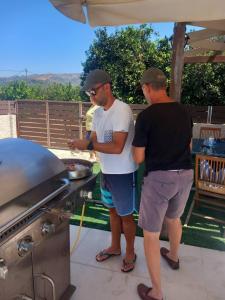 two men standing next to a barbecue grill at Giannis Villa in Skinés