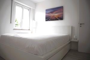 biała sypialnia z łóżkiem i oknem w obiekcie Calm and Cozy apartment Bivange w mieście Livange