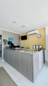 a lobby with a reception counter with a clock on the wall at Hotel Pousada Kairos Manaira in João Pessoa