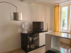 a room with a desk with a television and a fan at Studio de la fontaine in Romans-sur-Isère