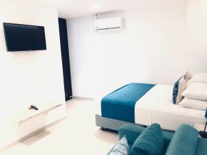 a bedroom with a bed and a couch and a tv at White Coral ApartaSuites in San Andrés