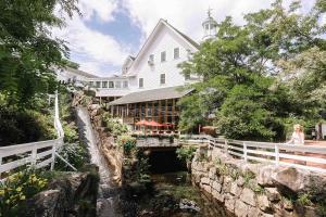 a woman standing in front of a building next to a river at Mill Falls Resort Collection at the Lake in Meredith