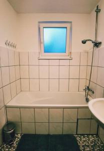 baño con bañera, lavabo y ventana en Ferienwohnung Sigmaringen, en Sigmaringen