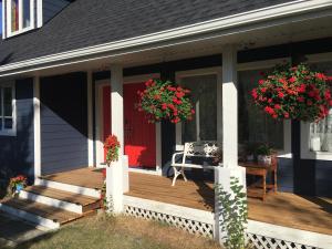 eine Veranda eines Hauses mit zwei Blumenkörben in der Unterkunft The Blue Cottage B&B in Seventy Mile