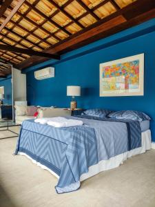 a blue bedroom with a bed and a blue wall at Casa Azul Hibisco - Geriba Buzios in Búzios