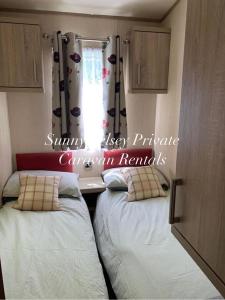 two beds in a small room with a window at Sea - esta in Selsey