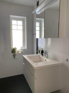 a white bathroom with a sink and a mirror at Ett rum & kök in Bålsta