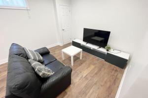 - un salon avec un canapé en cuir noir et une télévision dans l'établissement New and Cozy House 5min to Yonge and Finch, à Toronto