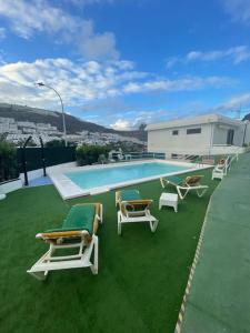 a group of lounge chairs and a swimming pool at Apartment Montaña Clara & pool in Mogán