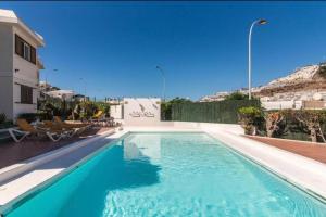 a swimming pool with blue water in a building at Apartment Montaña Clara & pool in Mogán