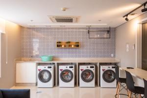 a laundry room with four washing machines and a counter at Studios aconchegantes no Setor Marista BLS in Goiânia