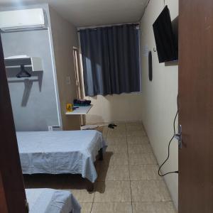 um pequeno quarto com 2 camas e uma televisão em Flat estação em Juazeiro do Norte