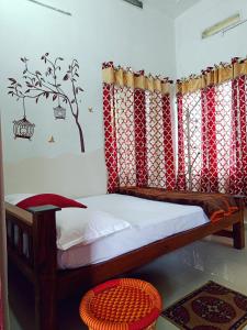 Schlafzimmer mit einem Bett mit roten und weißen Vorhängen in der Unterkunft Tranquil Meadows Hues in Kattappana