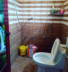 een badkamer met een douche, een toilet en emmers bij Tranquil Meadows Hues in Kattappana
