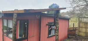 a red shed with a wooden roof and a window at REFUGIO CAMPESTRE A 7 MIN DE OSORNO in Osorno