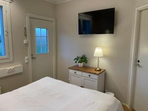 a bedroom with a white bed and a television on the wall at Puuppola Kotikoivu in Matinmäki