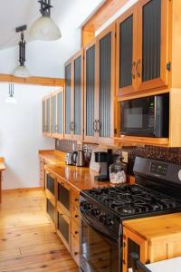 a kitchen with wooden cabinets and a stove top oven at The Doma Lodge - Cozy Muskoka Cabin in the Woods in Huntsville