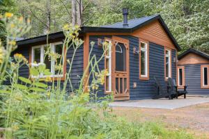 una casita azul con porche y patio en The Doma Lodge - Cozy Muskoka Cabin in the Woods, en Huntsville