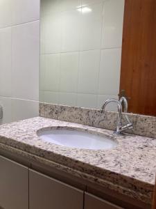 um balcão de casa de banho com um lavatório e um espelho em Casa completa e confortável em Leopoldina