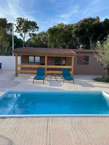 - une piscine avec 2 chaises et une maison dans l'établissement Grand chalet d’été avec piscine, à Bonifacio