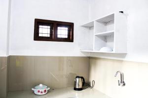 eine Küche mit weißen Schränken und einem Fenster über einem Waschbecken in der Unterkunft Tranquil Meadows Hues in Kattappana