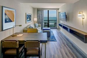 弗吉尼亚海滩Embassy Suites By Hilton Virginia Beach Oceanfront Resort的客厅里有一张桌子、一张沙发和一台电视