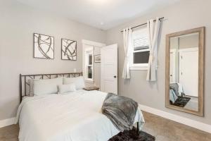 比尤特Modern condo in the heart of uptown Butte - Unit A的白色卧室设有一张大床和镜子