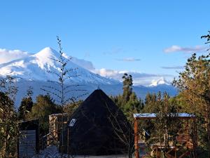 una montaña nevada en la distancia con una yurta en Casa Pumahue, en La Ensenada