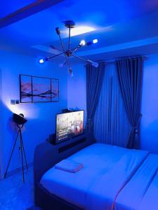 a blue bedroom with a bed with a television on it at Gilpins Classic Penthouse in Lekki