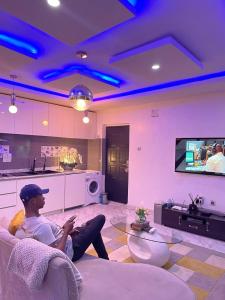 a man sitting on a couch in a living room at Gilpins Classic Penthouse in Lekki