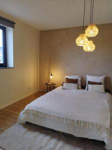 a bedroom with a large white bed and two lights at Au pied du mur in Huy