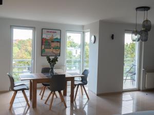 ein Esszimmer mit einem Tisch, Stühlen und Fenstern in der Unterkunft Apartament Wojskowa 1 / City Park in Posen