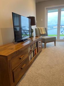 uma sala de estar com uma televisão de ecrã plano num centro de entretenimento em madeira em The Boathouse em One Tree Point