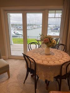 una mesa con sillas y un jarrón con flores. en The Boathouse, en One Tree Point