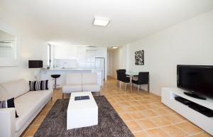 a living room with a white couch and a tv at Fairshore 28 Beachfront Escape in Noosa Heads