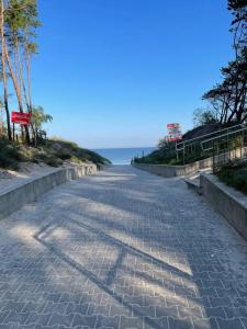 a cobblestone road next to a beach with the ocean at Apartament Gardenia Sun in Międzywodzie +13 photos