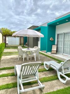 een patio met een tafel en stoelen en een parasol bij Casa - villa luisa a 100m do mar in Paripueira