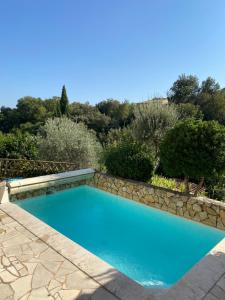 einen Pool in einem Garten mit einer Steinmauer in der Unterkunft La maison Provençale in Cotignac