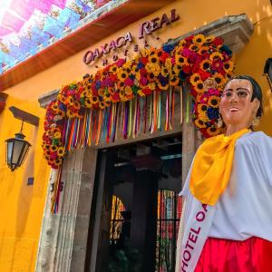 a woman standing in front of a building with flowers at Hotel Oaxaca Real in Oaxaca City