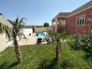 a backyard with a swimming pool and two palm trees at BakuHome in Baku