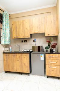 uma cozinha com armários de madeira e um frigorífico em Olive homes em Kampala