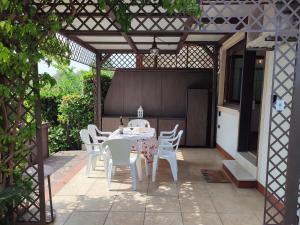 una mesa blanca y sillas bajo una pérgola en Le Petit Nid, en Toscolano Maderno