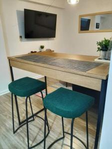 a counter with two green stools in a room at Miraflores Beautiful Studio! in Lima